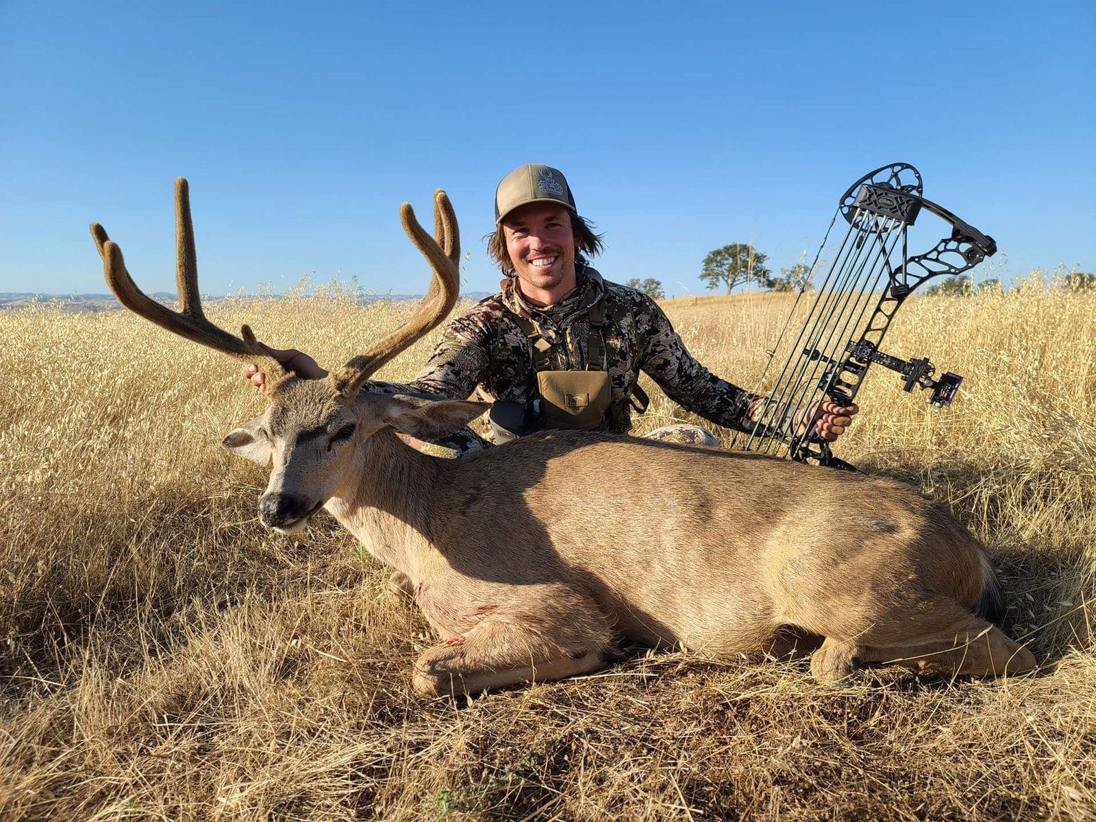 Hunter with a trophy Central Coast blacktail buck in golden grass