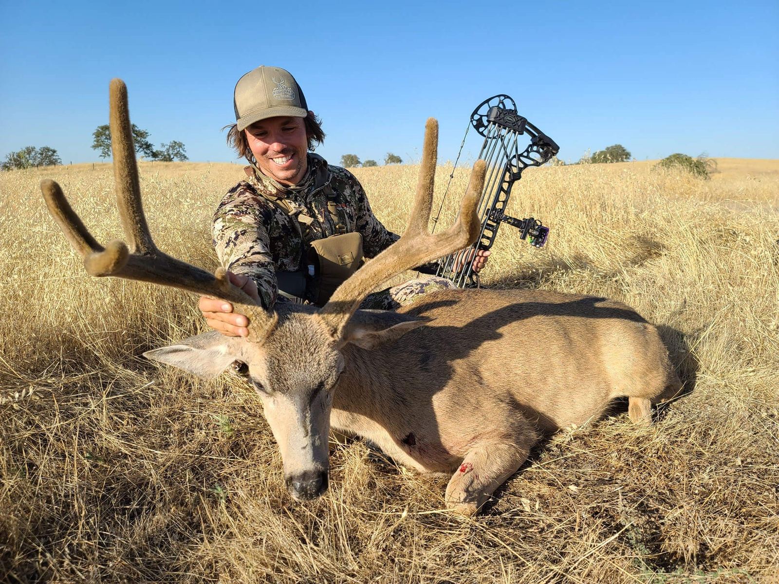 Bowhunter holding the antlers of a heavy blacktail buck
