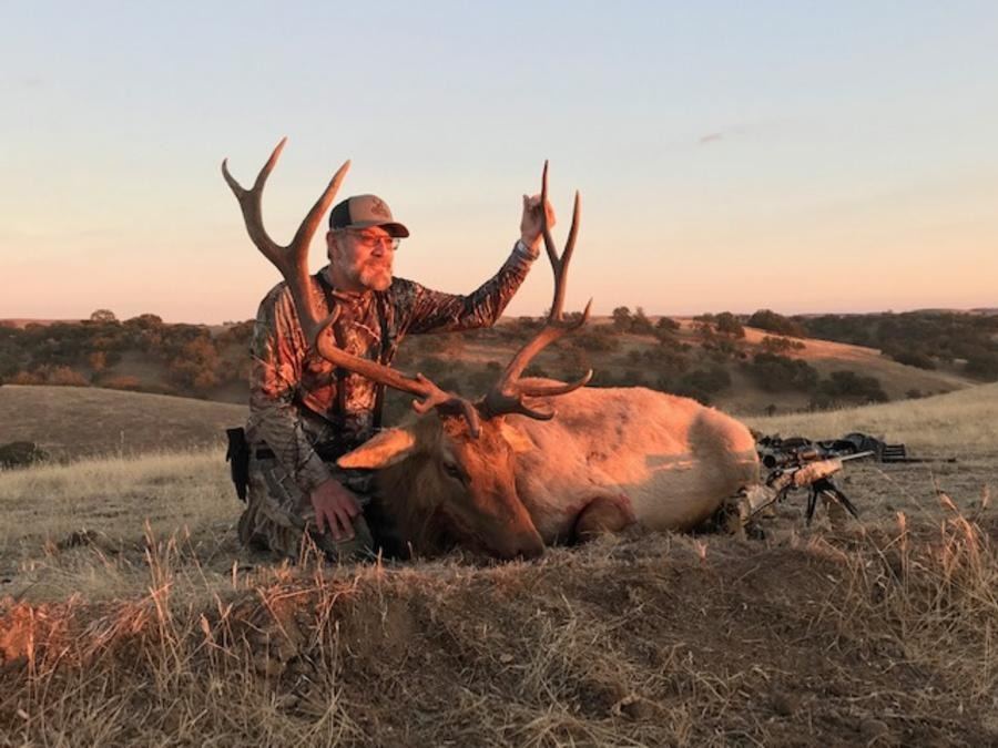 Hunter with a Tule elk bull in warm evening light